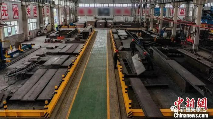 工人戴著口罩駕駛叉車卸下從河北運來的35噸鋼管材。第十二師供圖 生產車間